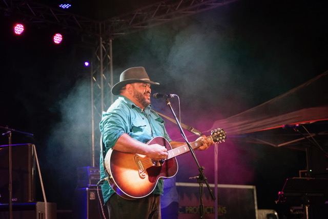 Bradley on an outdoor festival stage with his guitar